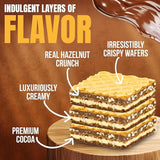 Layered dessert with hazelnut crunch, crispy wafers, and creamy filling on a wooden board.